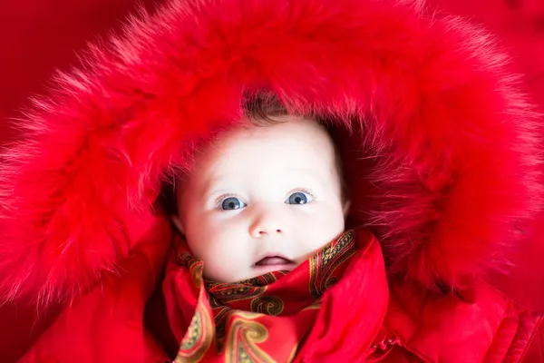 Babymeisje in een rode bont jas — Stockfoto