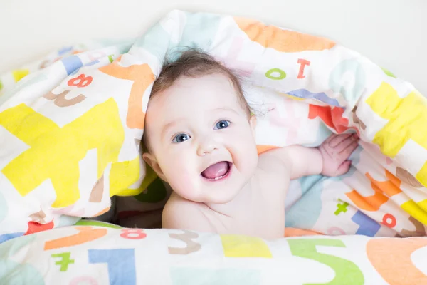 Bambino sotto una coperta colorata — Foto Stock