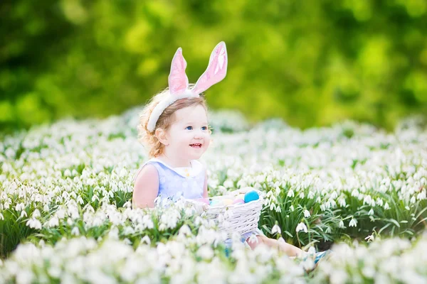 Menina vestindo orelhas de coelho jogando com ovos de Páscoa — Fotografia de Stock