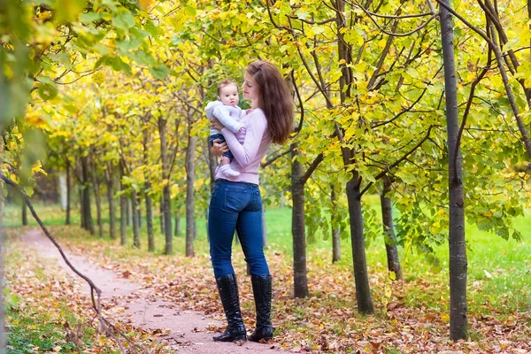 Madre che cammina con il suo bambino in un parco autunnale — Foto Stock