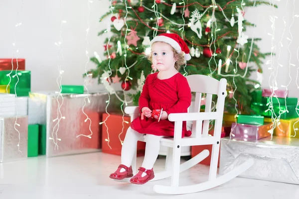 Kırmızı bir elbise ve santa şapka yürümeye başlayan çocuk kız — Stok fotoğraf