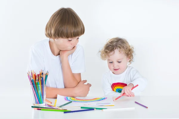 Peuter meisje tekenen met kleurrijke potloden en haar broer — Stockfoto