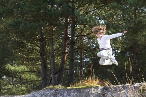 Boy jumping in pinewood forest — Stock Photo, Image