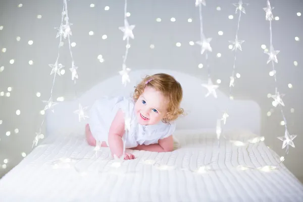 Petite fille jouant sur un lit blanc — Photo
