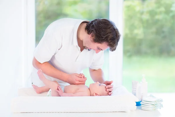 Jonge liefhebbende vader veranderen luier van zijn zoon pasgeboren baby — Stockfoto