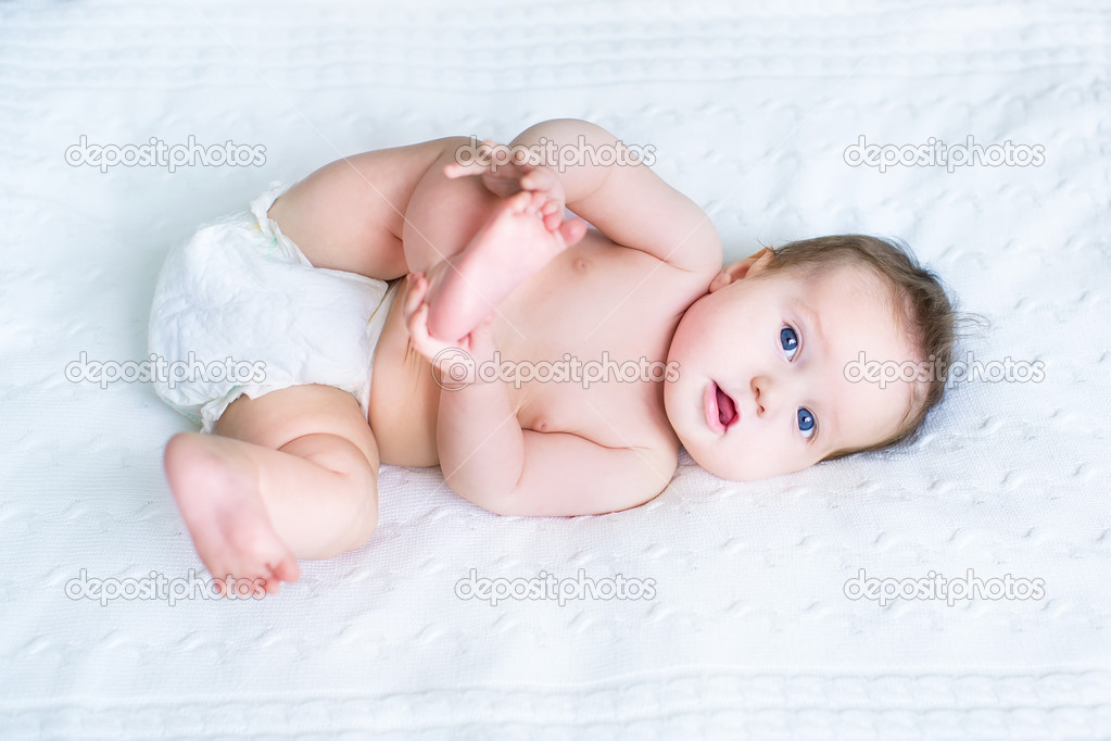 Laughing baby wearing a diaper playing with her feet