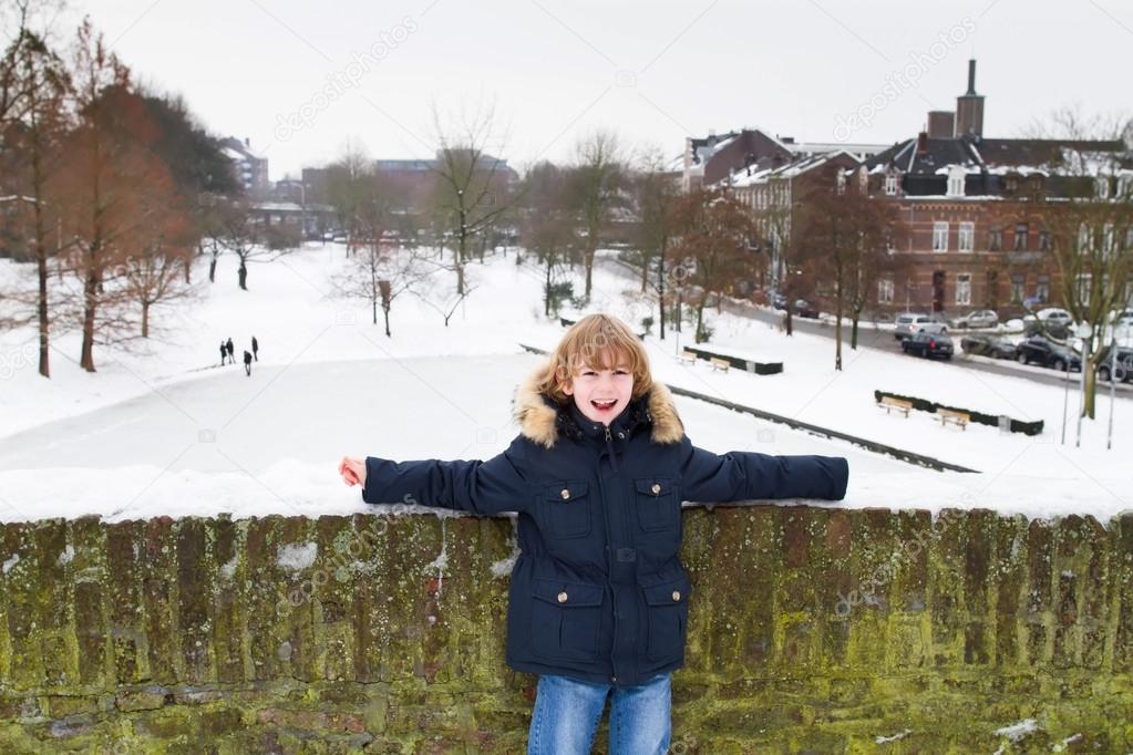 Boy standing on a bridge over a frozen lake