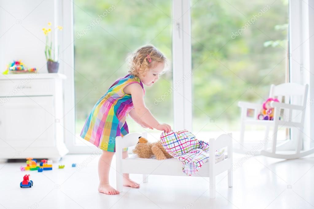 Toddler girl playing with her teddy bear