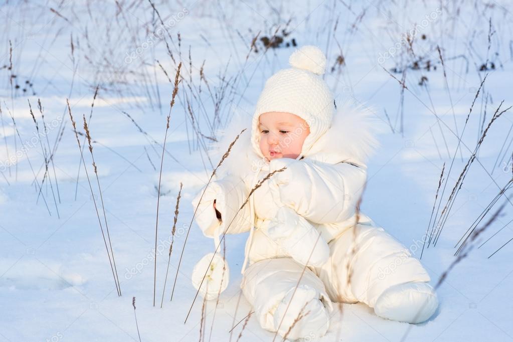 Funny baby playing with grass in a snow field