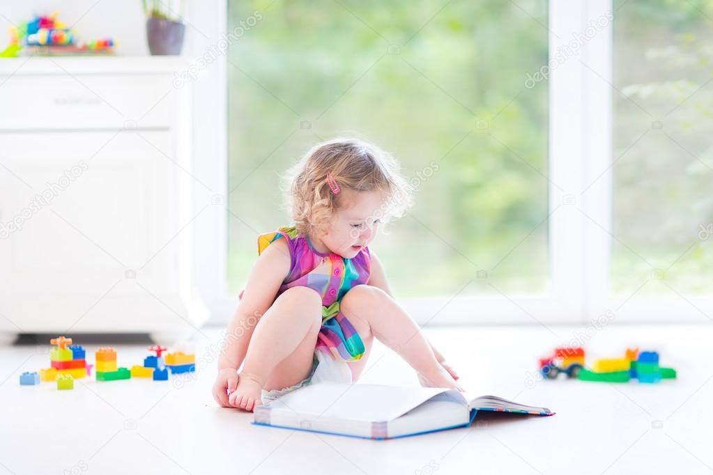 Girl with blond curly hair reading a book