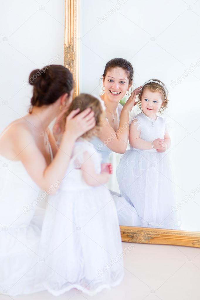 Mother and her toddler daughter standing in front of a big mirror