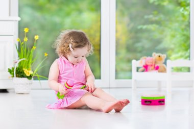 Tef güneşli beyaz odada oynayan sevimli kıvırcık yürümeye başlayan çocuk kız