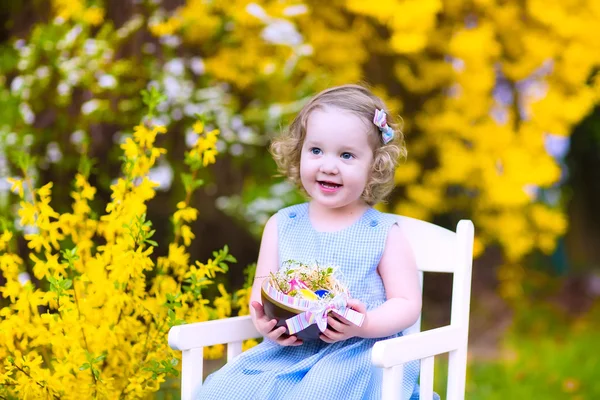 Cute curly toddler girl enjoying egg hunt in the garden — Stock Photo, Image