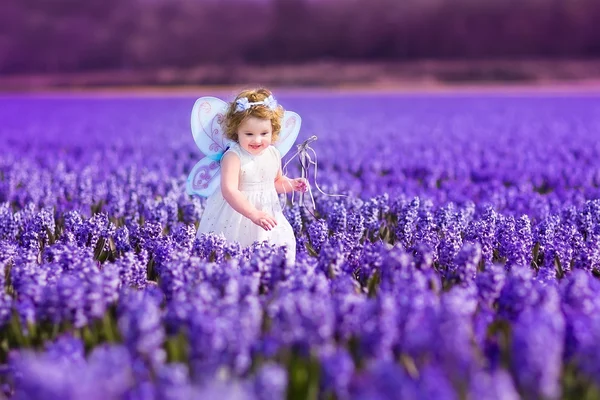 Девочка в сказочном костюме играет на цветочном поле — стоковое фото
