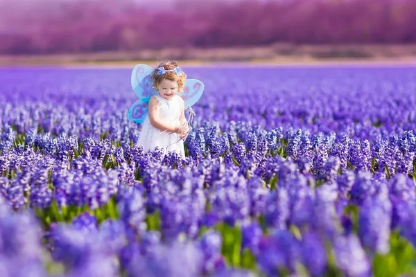 Schattig peuter meisje in fee kostuum in een bloem veld — Stockfoto