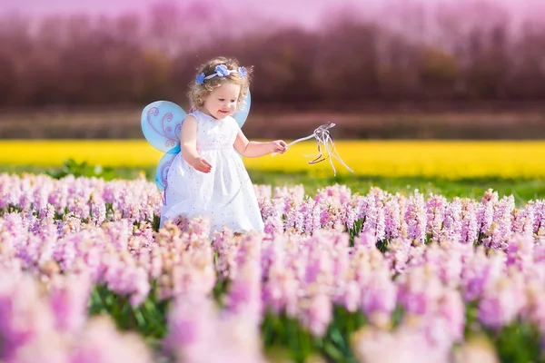 Schattig peuter meisje in fee kostuum in een bloem veld — Stockfoto