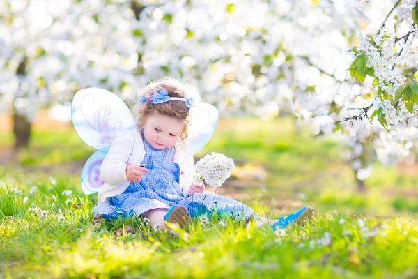 Gekrulde peuter meisje in fee kostuum spelen in vrucht tuin — Stockfoto