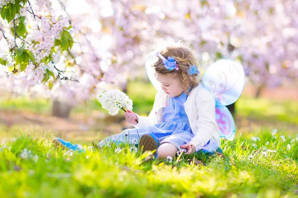 Curly toddler girl in fairy costume playing in fruit garden — Stock Photo, Image