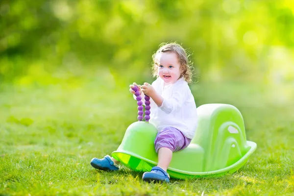 Peuter meisje op een schommel in een zonnige tuin — Stockfoto