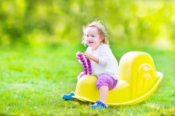 Toddler girl on a swing in a sunny garden — Stock Photo, Image