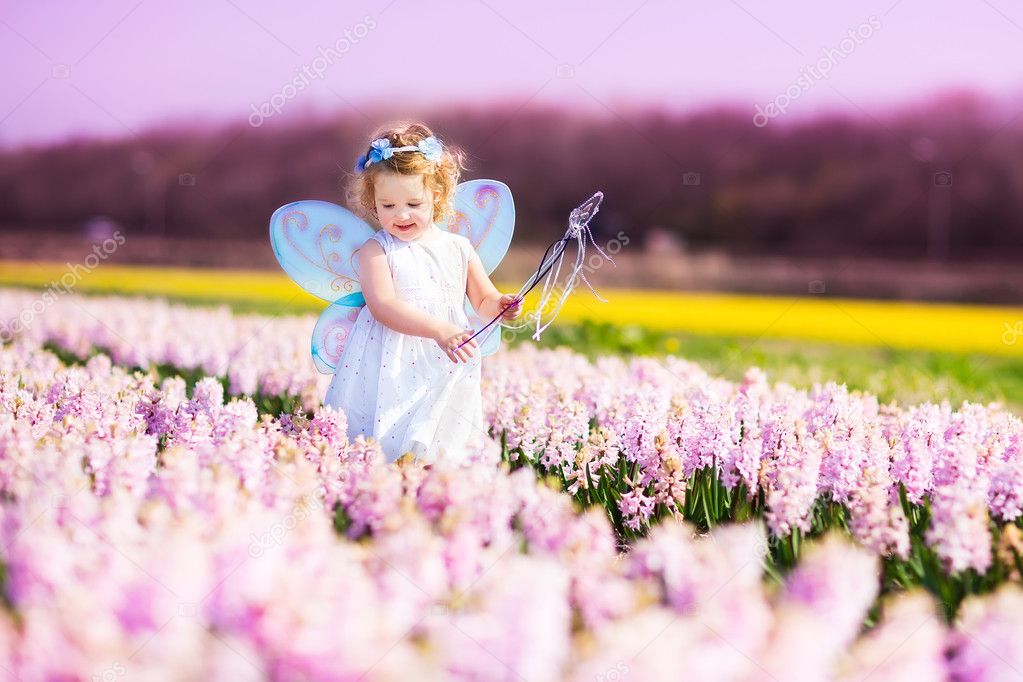 Cute toddler girl in fairy costume in a flower field