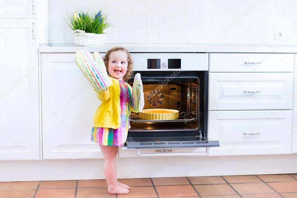 Toddler girl with an apple pie in the oven