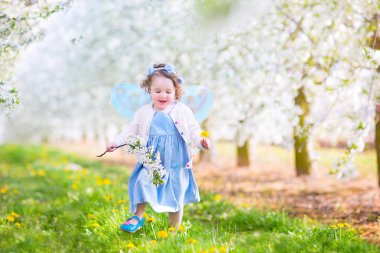 fille mignon bambin en costume de fée jouant dans un jardin fleuri