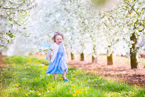 Linda niña en traje de hadas jugando en un jardín floreciente — Foto de Stock