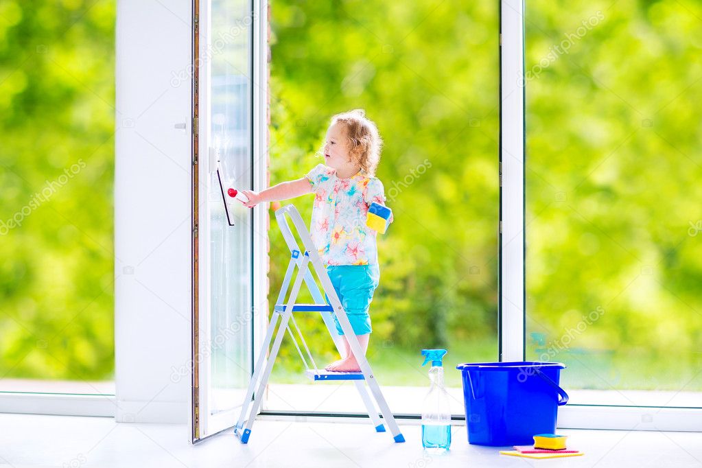 Little girl washing a window