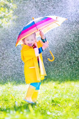 Funny toddler with umbrella playing in the rain clipart