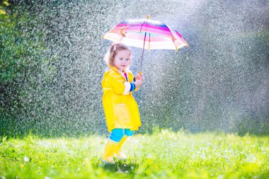 Funny toddler with umbrella playing in the rain clipart