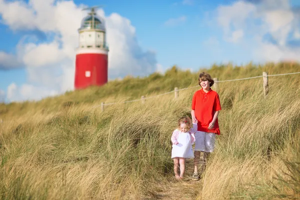 Brother and sister playing on the beach next to a lighthouse — Stock Photo, Image
