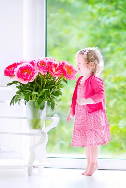 Kleinkind spielt mit Pfingstrosenblumen — Stockfoto