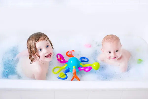 Two little kids playing in a bath tub with toys — Stock Photo, Image