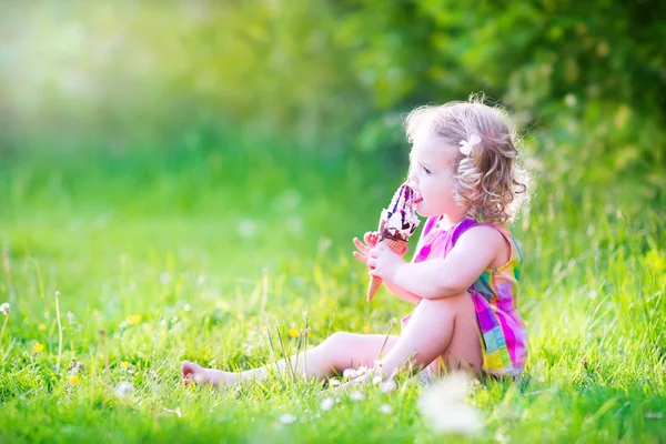 Забавная девушка ест мороженое в саду — стоковое фото
