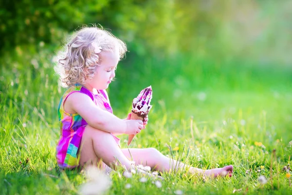 Забавная девушка ест мороженое в саду — стоковое фото