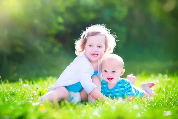 Hermano pequeño y hermana pequeña en un jardín — Foto de Stock