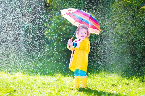 Bébé drôle avec parapluie jouant sous la pluie — Photo