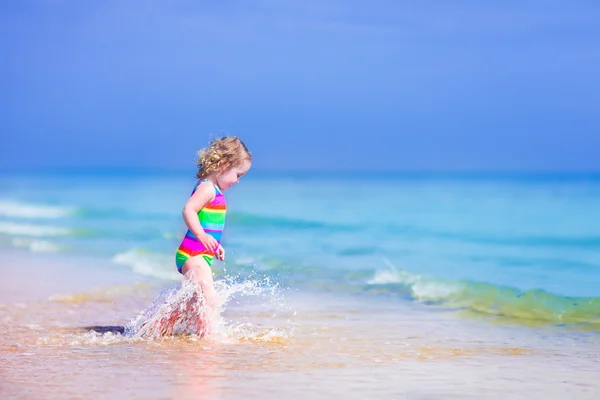 Liten flicka som körs på en strand — Stockfoto