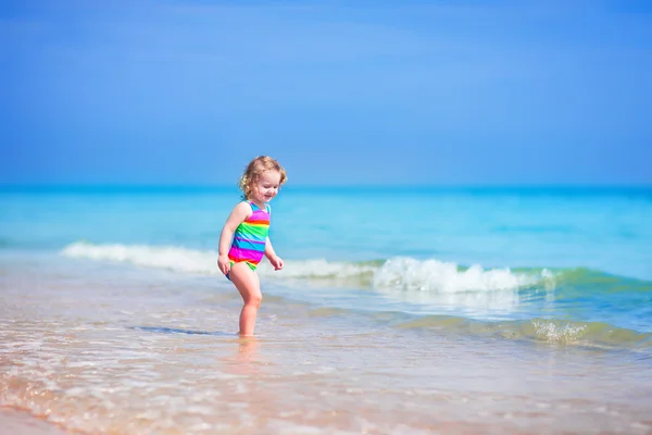 Liten flicka som körs på en strand — Stockfoto