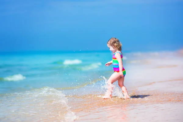 Liten flicka som körs på en strand — Stockfoto