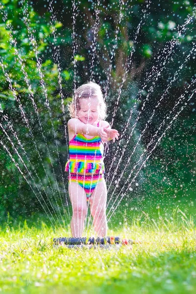 Menina brincando com aspersor de jardim — Fotografia de Stock