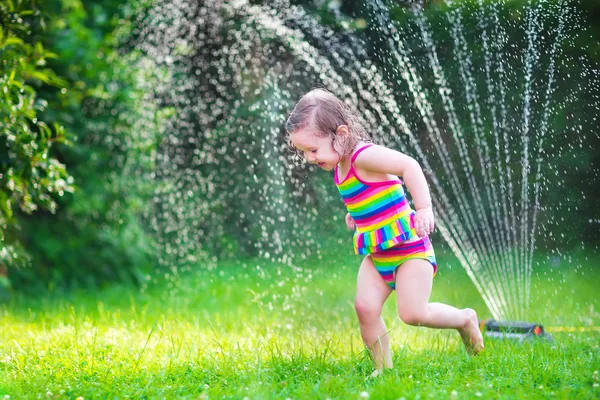 Ragazzina che gioca con irrigatore giardino — Foto Stock