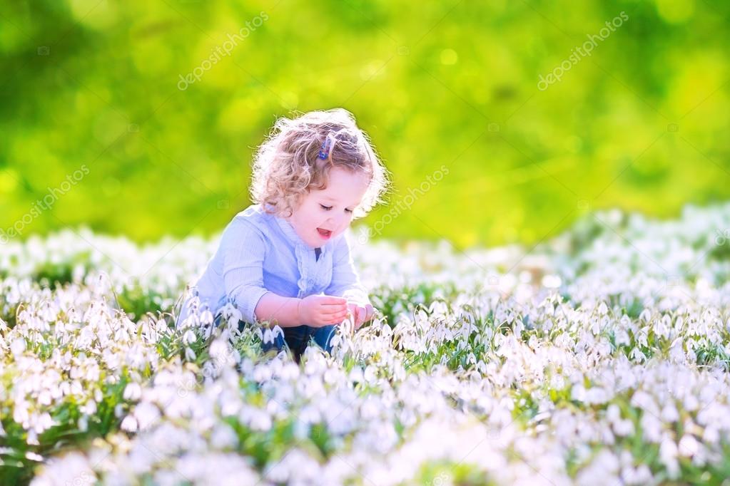 Happy girl playing with first spring flowers