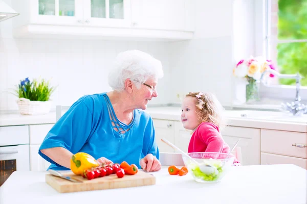 Grootmoeder en meisje maken salade — Stockfoto