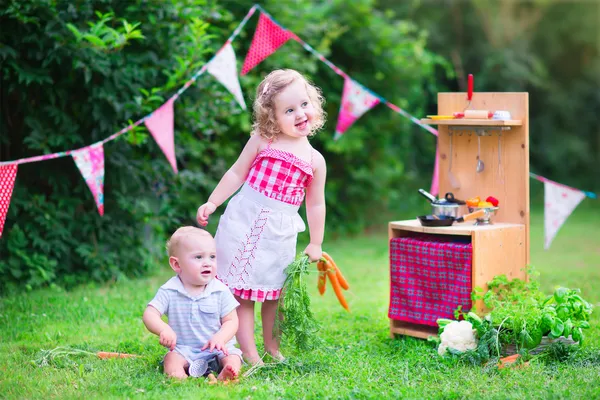 Malé děti hrát s hračkou kuchyní v zahradě — Stock fotografie