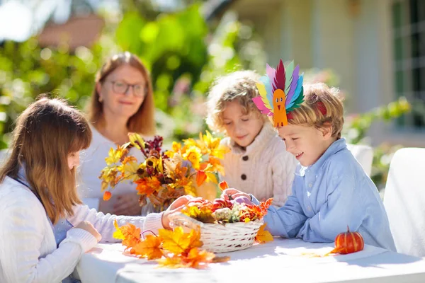 Family celebrating Thanksgiving. Kids autumn arts and crafts. Little boy with pumpkin and turkey hat at decorated table. Happy celebration on sunny fall day. Child decorating home.