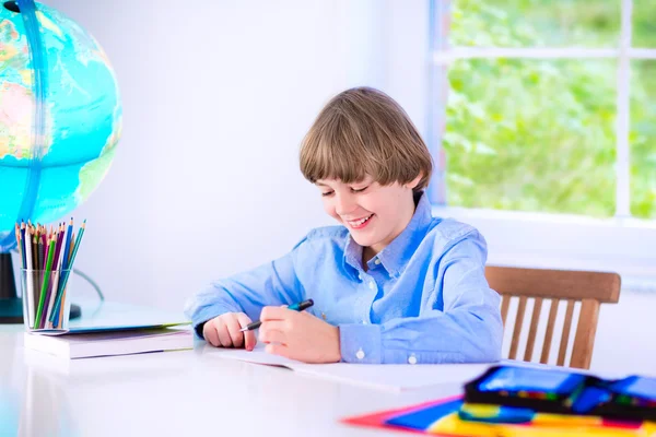 Улыбающийся мальчик, выполняющий домашнюю работу — стоковое фото