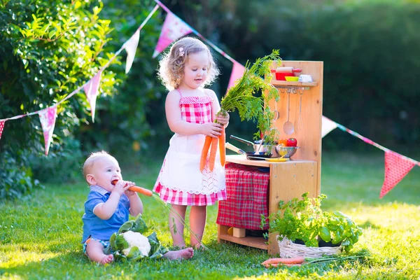 Маленькі діти грають з іграшковою кухнею в саду — стокове фото