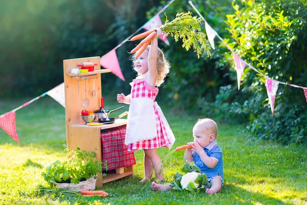 Niños pequeños jugando con la cocina de juguete en el jardín —  Fotos de Stock